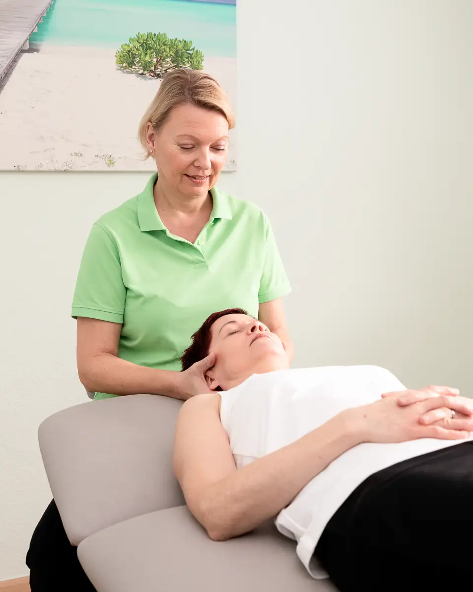 Physiotherapeutin unterstützt Patientin bei Übungen auf der Therapieliege